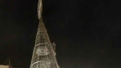 Un joven escala de noche el árbol de Navidad gigante de la plaza de la Constitución de Málaga