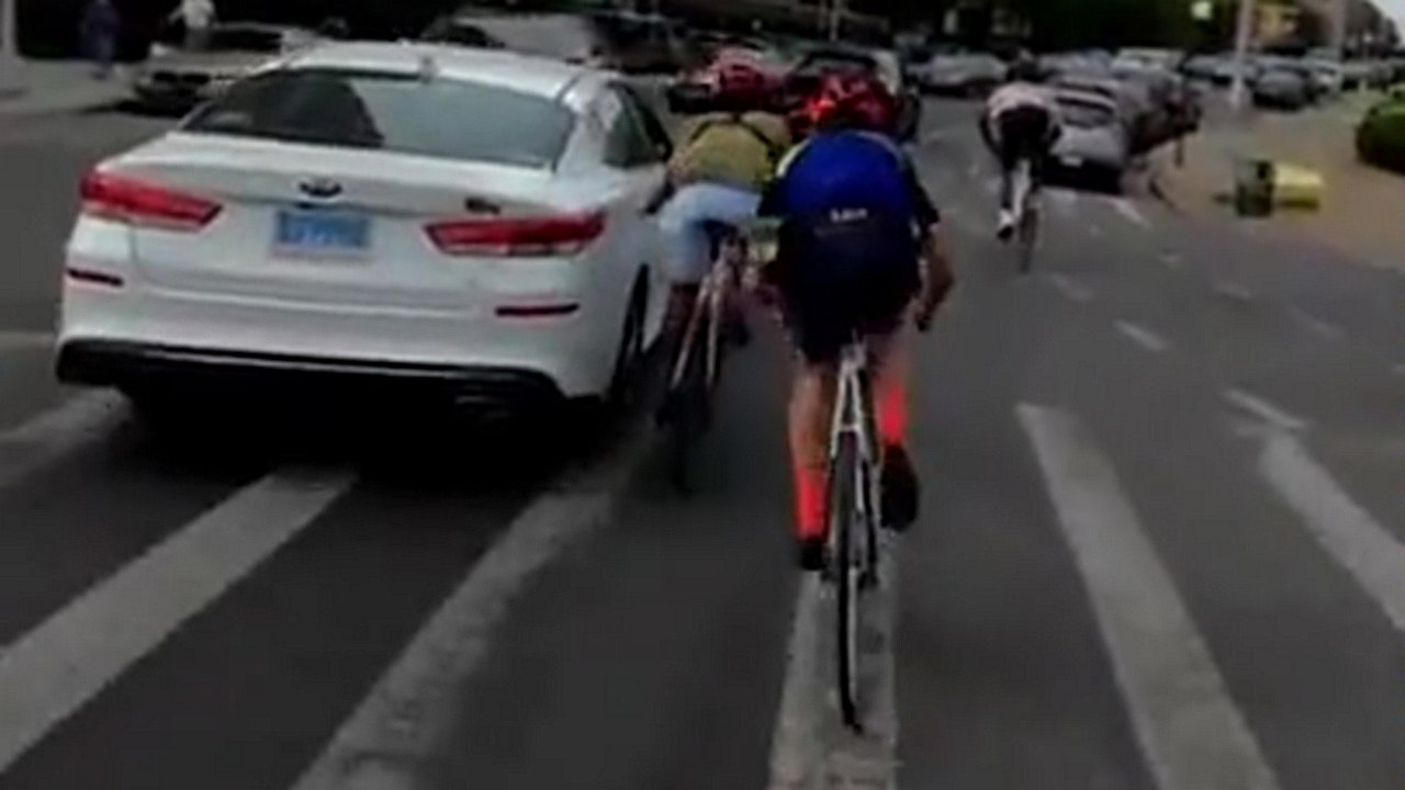 Deux cyclistes s'accrochent à une voiture