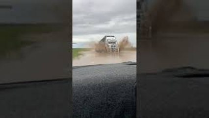 Truck Driving on Flooded Roads Covers Car