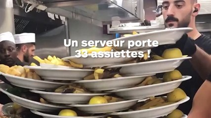 Un serveur empile 33 assiettes avant de servir en salle