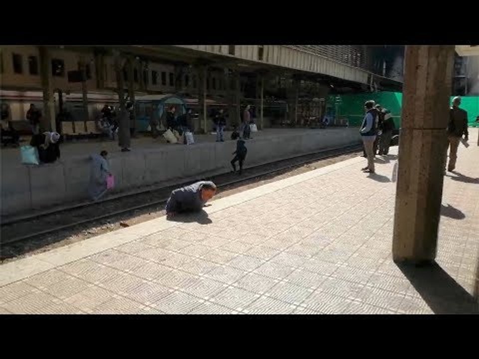مواطنون يعبرون قضبان السكة الحديد من موقع حريق محطة مصر