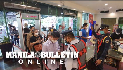 People show their vaccination cards upon entering a mall in Manila