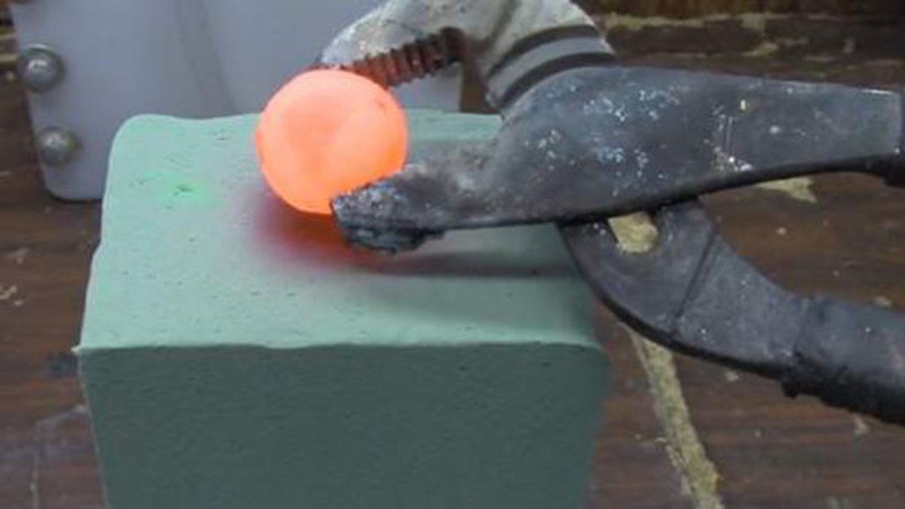 Vollidiot legt glühende metallkugel auf einen blumensteckschaum...