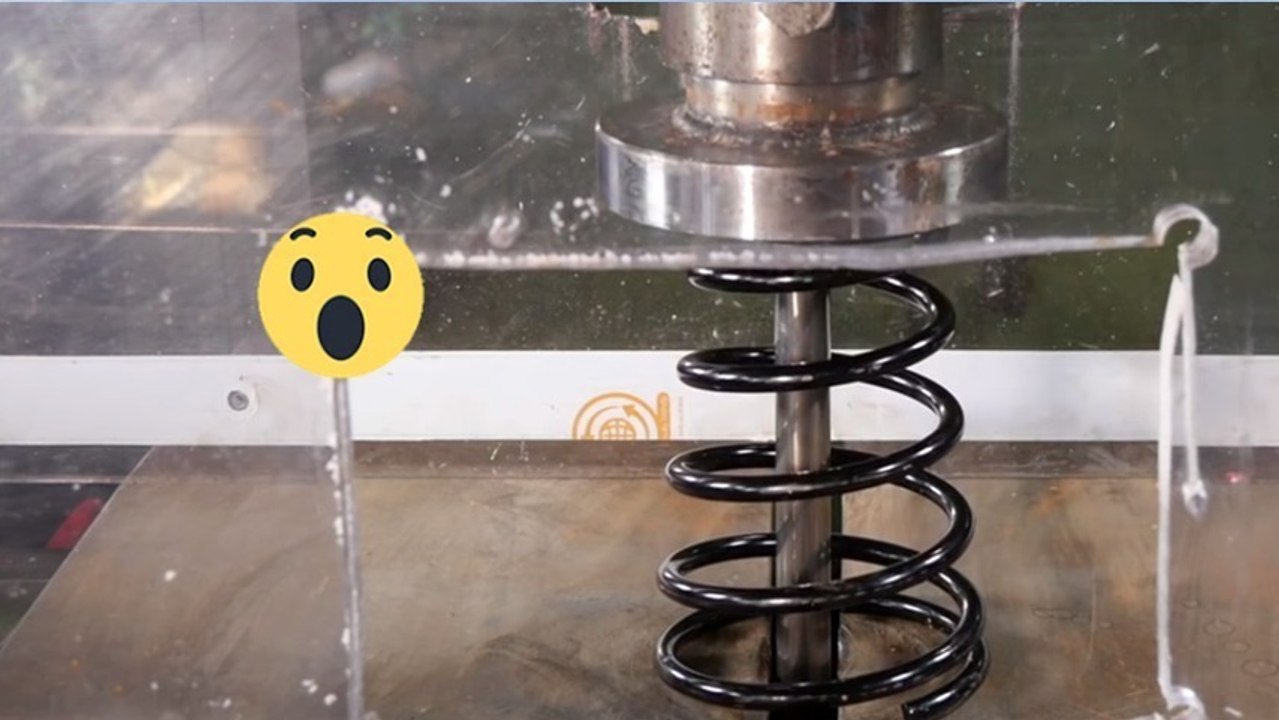 Eine Hydraulikpresse zerquetscht einen Stoßdämpfer