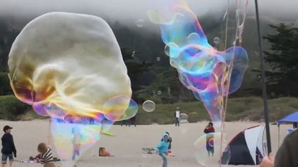 Il réalise des bulles géantes sur une plage