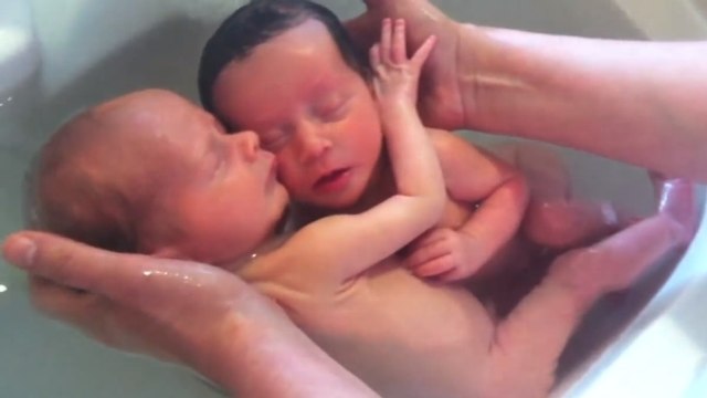 Ces bébés jumeaux se tiennent l'un à l'autre dans leur bain. Ils sont vraiment adorables
