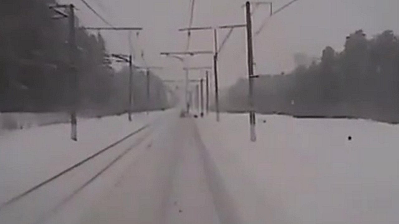 Des employés travaillent sur une ligne de chemin de fer quand un train arrive