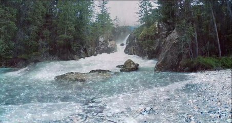 The heavy rain falls into a strong flowing waterfall in the rainforest