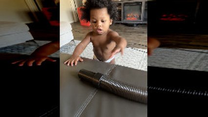 Baby Playing with Vacuum Puts Hose to Face