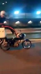 A "vida louca" de um entregador de comida ao conduzir a mota sentado na caixa térmica e com os pés sobre o guiador