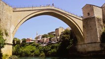 A bridge diver is sitting on metal fence at Old Bridge in Mostar