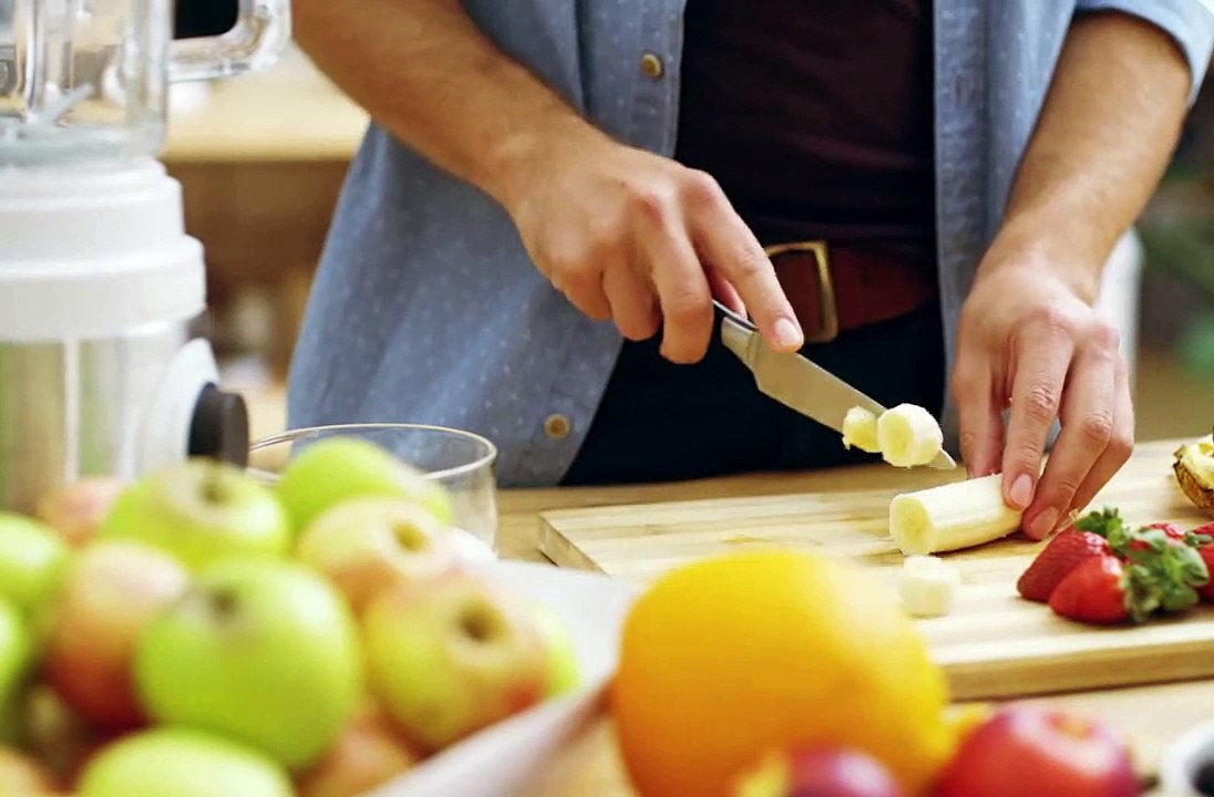 Cutting banana with knife with other fruits aside
