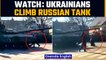 Ukrainians climb on top of Russian tanks in an effort to stop Russian military convoy |Oneindia News