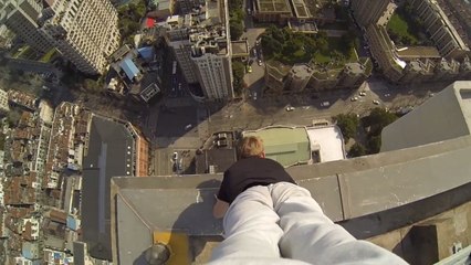 Scott Young risque sa vie en faisant le poirier sur la corniche d'un immeuble