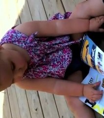 A un an, cette petite fille essaye de lire un magazine comme on utilise un iPad