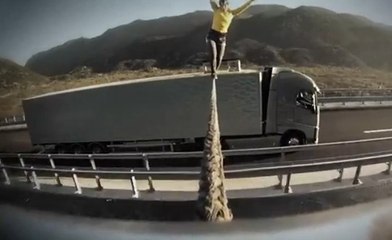 Elle fait de l'équilibre entre deux camions en marche
