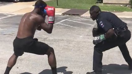 Un policier offre une leçon de boxe à un jeune sur un parking