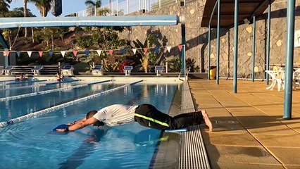 Un coach réalise des extensions abdominales au dessus d'une piscine