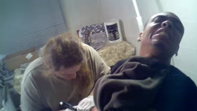 Il a du mal à contenir sa douleur pendant qu'il se fait tatouer