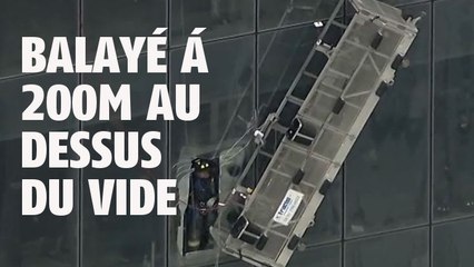 Des laveurs de vitres balayés par le vent sur un immeuble