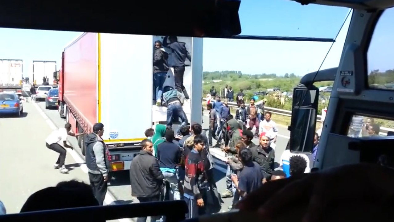 Des migrants prennent d'assaut un camion pour passer la frontière à Calais