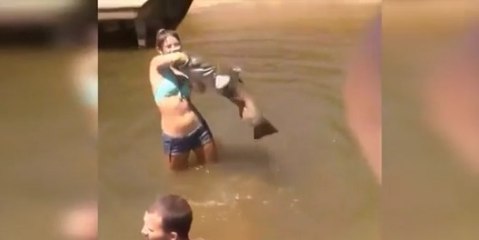 Une jeune femme attrape un poisson géant à mains nues