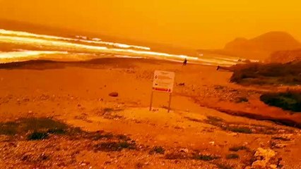Una playa con cielos naranjas por el polvo en suspensión