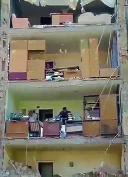 Homem recolhe pertences em prédio destruído pelos bombardeamentos em Kyiv