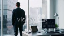 The cryptocurrency miner standins in his office and monitors stock exchange activity using infographics