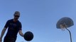 Man Shoots Couple of Different Trick Shots With Basketballs While Balancing on Rolling Board