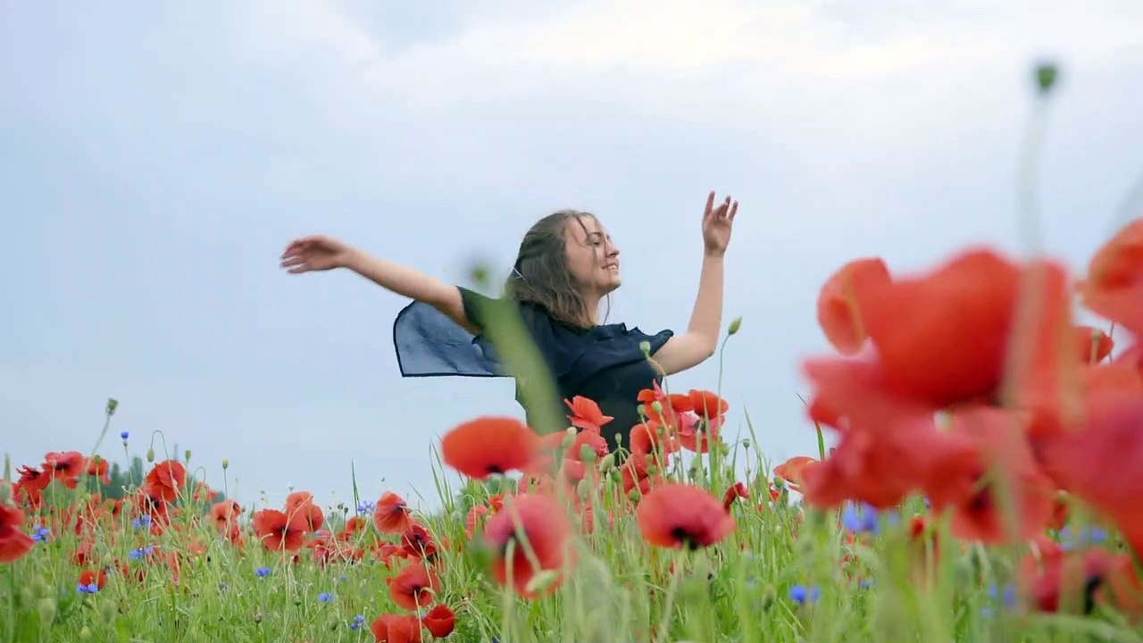 Girl dancing happily in a field of flowers Girl dancing happily in the middle of a field of pink and blue flowers, during a bright day.