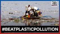 Fisherman paddles through plastic waste in fish port