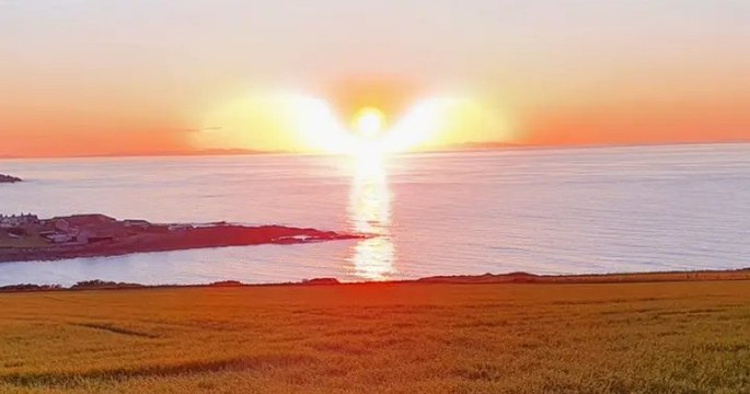 Sur cette photo unique, le soleil et la mer prennent la forme d'un ange avec des ailes pendant un coucher de soleil