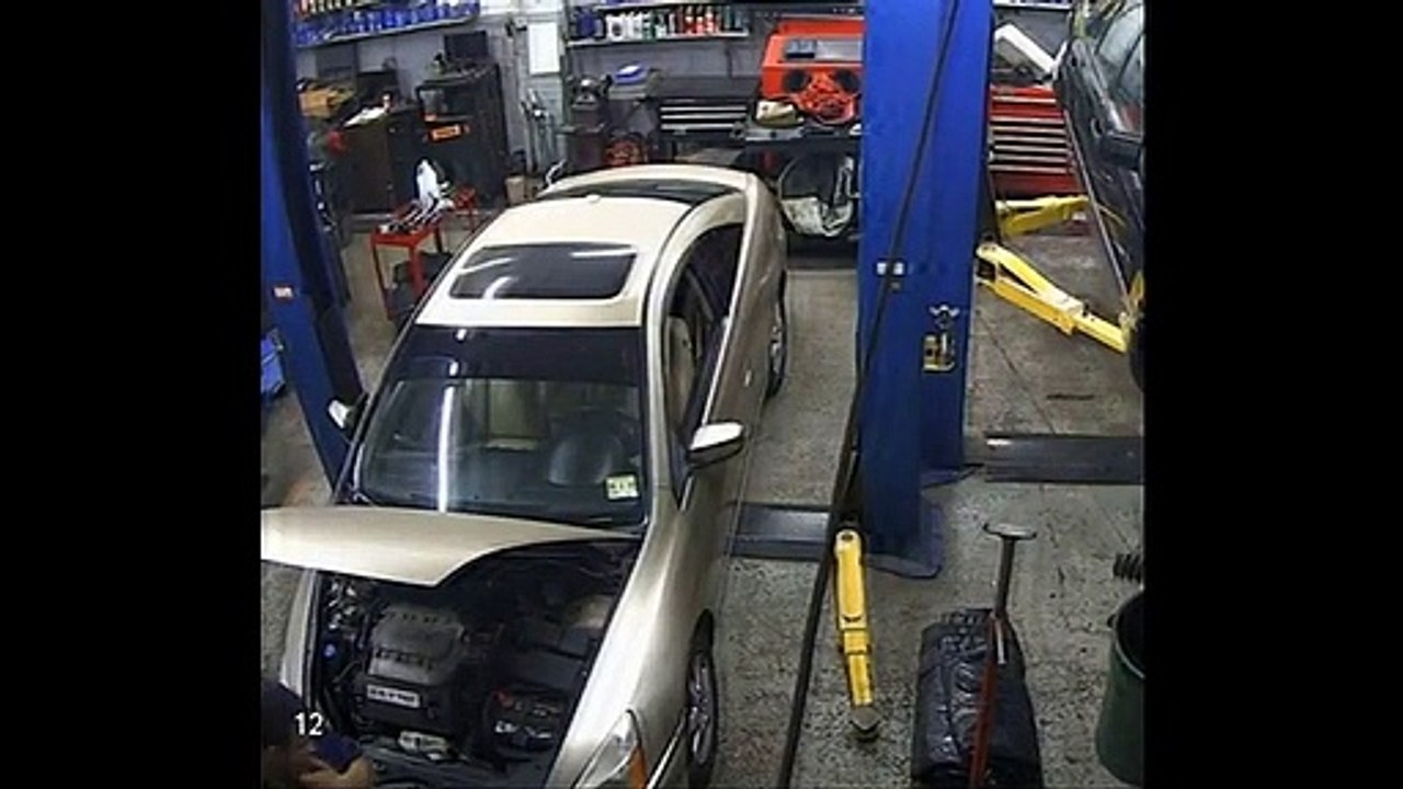 Un mécanicien se coince les coins dans le capot d'une voiture