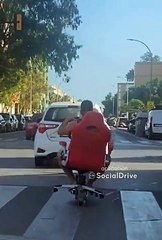 Circula en patinete eléctrico sentado en una silla de escritorio