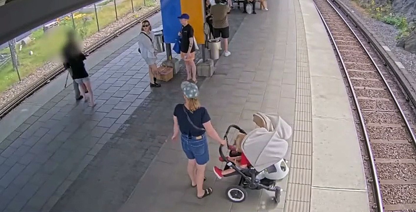 Une femme pousse un homme en béquille sur les rails du train dans une gare (Stockholm)