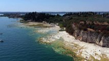 Lago di Garda, livello bassissimo delle acque per siccità: a Sirmione spunta una spiaggia di roccia