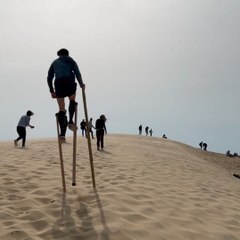 Julien grimpe la dune du Pilat sur ses échasses landaises