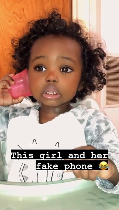 Little girl pretends to have phone call with an empty cup