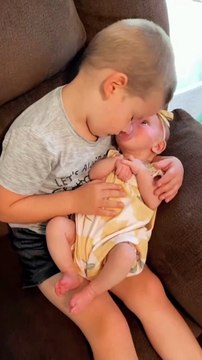 Big brother sweetly cuddles his new baby sister