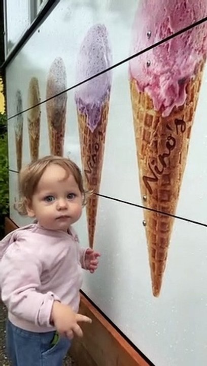 Confused toddler tries licking picture of ice cream cone