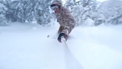 Person Slides Down Snow Covered Hill on Snowboard