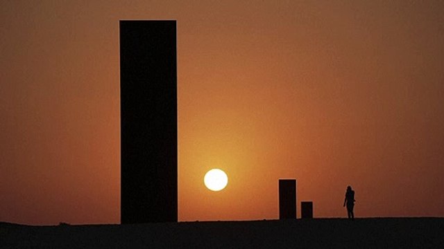 غروب الشمس خلال اكتمال القمر خلف عمل الفنان سيرا في قطر الذي يحمل عنوان شرق-غرب/غرب-شرق
