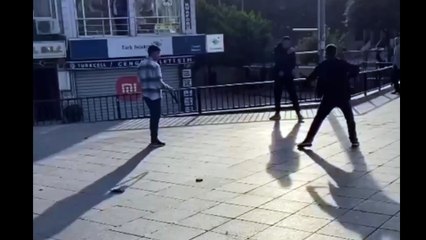 Üç genç meydanın ortasında birbirine girdi, kemerler havada uçuştu