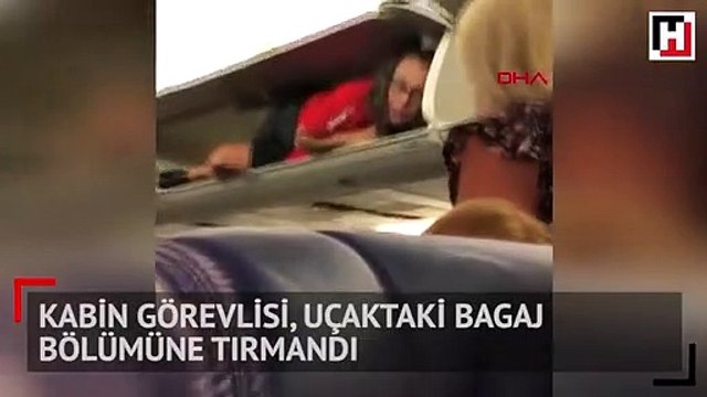 Kabin görevlisi, uçaktaki bagaj bölümüne tırmandı