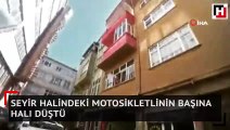 Seyir halindeki motosikletlinin başına halı düştü