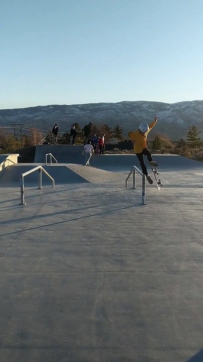 Boy on skateboard attempts boardslide at skatepark and stomach lands on rail
