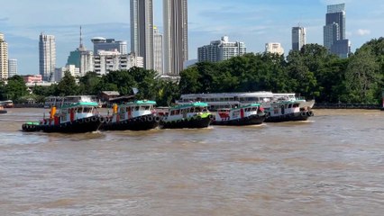 5 tugboats pulling huge barge at Chao Phraya river in Bangkok Thailand