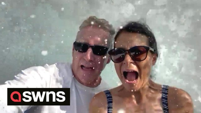 Couple get hilariously splashed and knocked over by huge wave while recording holiday video