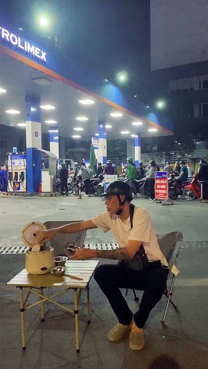 Thanh niên tranh thủ làm bát cơm nóng trong lúc xếp hàng chờ đổ xăng